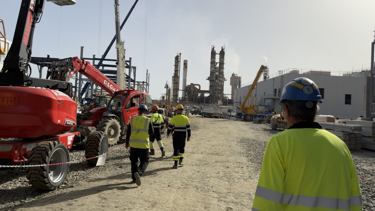 Equipa técnica em montagem industrial de refinaria com grua